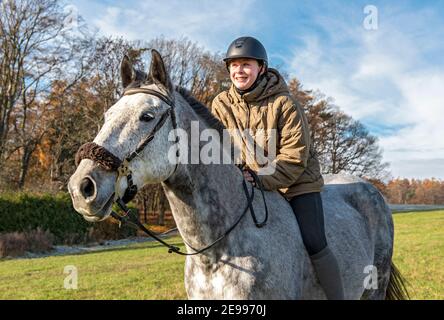 Young woman rides bareback on thoroughbred Czech warmblood horse in the fields Stock Photo