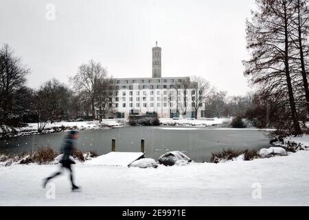 Brunswick, Germany. 02nd Feb, 2021. A jogger runs along a frozen pond in Kiryat Tivon Park. In the background, a hotel stands in front of the pressure tower of a river waterworks on the Oker, known as the 'water tower'. Credit: Stefan Jaitner/dpa/Alamy Live News Stock Photo