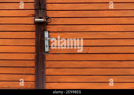 Orange painted wooden door with metal handle garage antique balkan aged with rusted metal bars Stock Photo