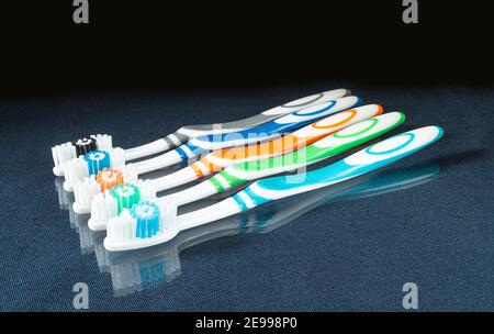The Set of the toothbrushes on glass table with reflection.Instruments for hygiene on black background Stock Photo