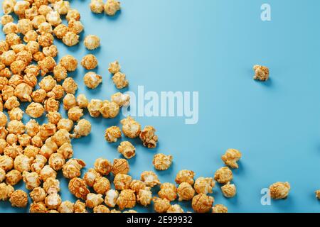 Popcorn is scattered on a blue background, in the form of a frame. Yummy for the filming of movies, TV series, cartoons. Free space, top view Stock Photo