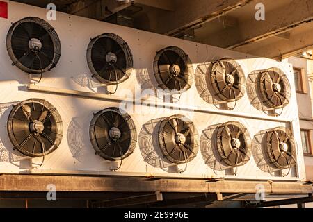 Condenser fan unit installed lined on the side of the building. Condenser fan unit for cooling of the air conditioning system. Stock Photo