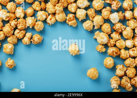 Popcorn is scattered on a blue background, in the form of a frame. Yummy for the filming of movies, TV series, cartoons. Free space, top view Stock Photo