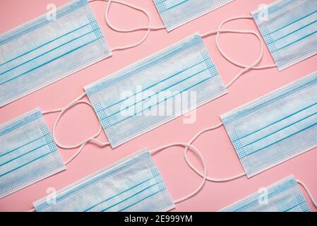 Geometric pattern made with protective surgical masks on pink background.Covid 19 concept