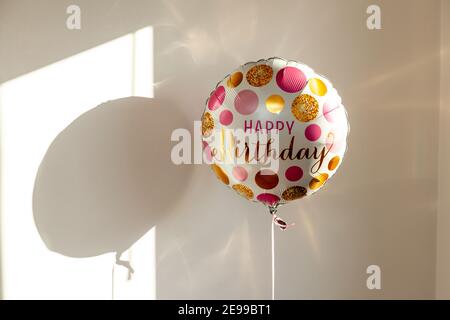 A happy birthday balloon lit by sunshine causing sparkles and shadows. Stock Photo