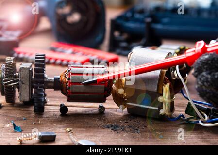 Power tool repair. Details of electrical appliance and repair tools on a wooden table in a repair shop Stock Photo