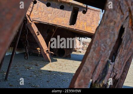 San Gregorio, Argentina-27.11.2018 old rusty and rotten ship wreck with holes in carcass, lying behind long gras on the beach of the coast line of the Stock Photo