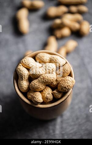 Roasted peanuts. Tasty groundnuts in cup on tablecloth. Stock Photo