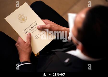 Washington, DC, USA. 3rd Feb, 2021. A guest holds a copy of the program from the Congressional Ceremony memorializing U.S. Capitol Police Officer Brian D. Sicknick, 42, lie in honor in the Rotunda of the Capitol on Wednesday, February 3, 2021. Officer Sicknick was responding to the riot at the U.S. Capitol on Wednesday, January 6, 2021, when he was fatally injured while physically engaging with the mob. Members of Congress paid tribute to the officer on Wednesday morning before his burial at Arlington National Cemetery. Credit: Demetrius Freeman/Pool Via Cnp/Media Punch/Alamy Live News Stock Photo