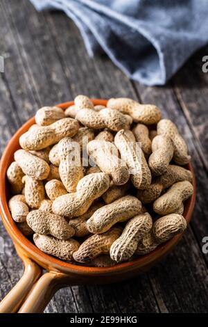 Roasted peanuts. Tasty groundnuts in pot on wooden table. Stock Photo