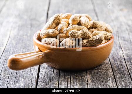 Roasted peanuts. Tasty groundnuts in pot on wooden table. Stock Photo