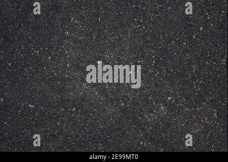 Direct overhead shot of the rough texture of dark asphalt filled with shiny stones that resemble a starry sky. Stock Photo