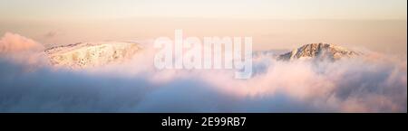 Peaks emerge from the clouds at sunset Stock Photo