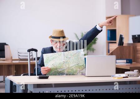 Aged male employee preparing for travel in the office Stock Photo