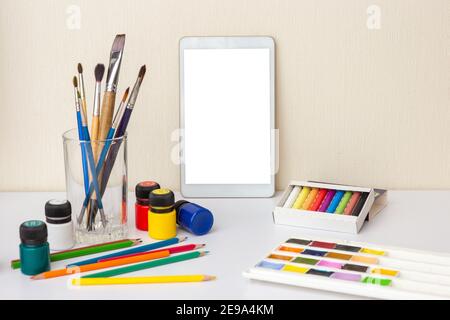 White table with digital tablet with blank screen on white table with colorful drawing supplies Stock Photo