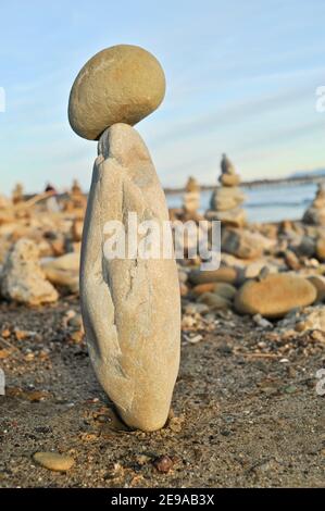 Smooth, oddly shaped rocks and stones piled up tall, balanced precariously, at sunset, California coast, USA Stock Photo