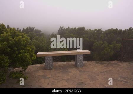 Image of a stone bench in a rest area in a forest surrounded by fog with copy space Stock Photo