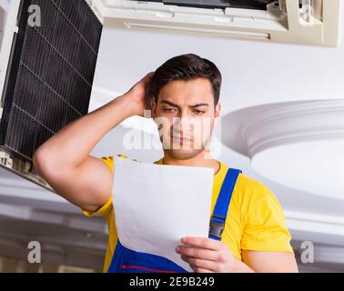 The repairman repairing ceiling air conditioning unit Stock Photo