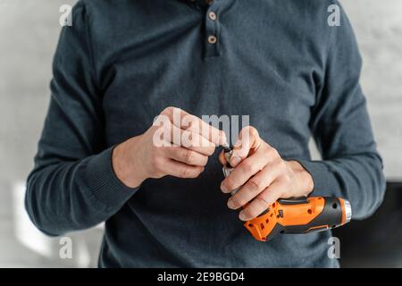 Men's hands in work gloves with a yellow screwdriver screw the roofing  sheet to the roof of a country house. Cordless drill Stock Photo - Alamy