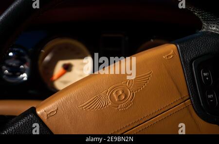 Selective focus on brown leather steering with engraved Bentley logo wheel with blurry view on dashboard Stock Photo