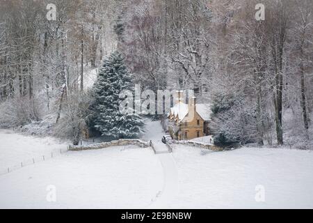 Cotswold cottage in the snow on the edge of a woodland. Lower Coscombe, Cotswolds, Gloucestershire, England Stock Photo