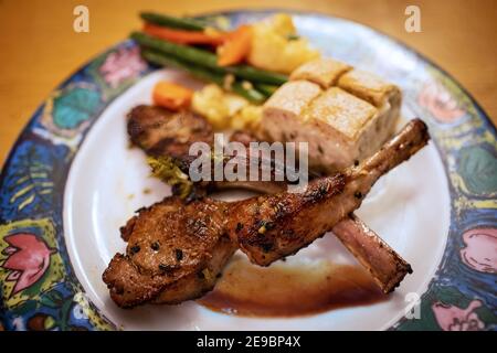 Gourmet grilled rack of lamb chops with garlic and wine served with vegetables. Stock Photo