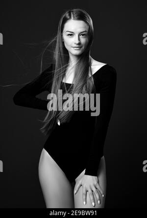 Black and white portrait of smiling young pretty woman with long silky straight hair in black bodysuit with long sleeves Stock Photo