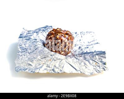Round chocolate candies in a foil wrapper on a white background. Sweet cake. Silver wrapper. Shiny foil. Candy wrapper. Sweet dessert. White backgroun Stock Photo