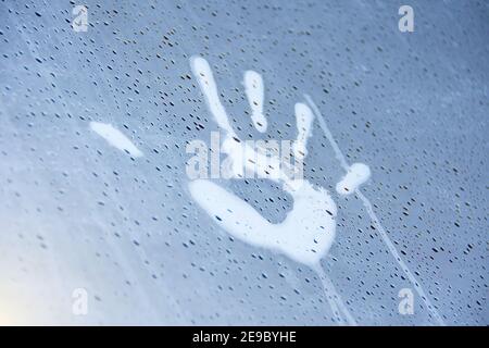 Palm print on misted glass with water drops flowing down Stock Photo