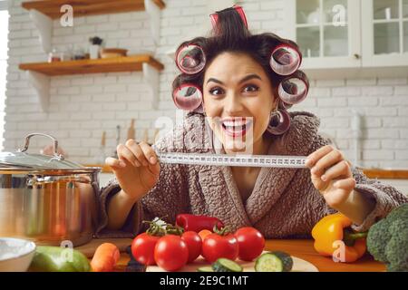 Funny housewife holding a tape measure and showing how much weight she has lost on a diet Stock Photo