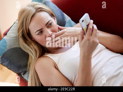 Woman looking shocked looking at message Stock Photo