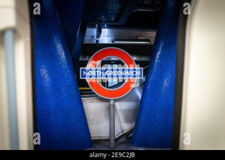 North Greenwich Underground Station, London Platform TFL sign red and blue taken looking out from train carriage through closing doors on underground Stock Photo
