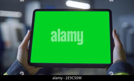 Industry 4.0 Factory: Chief Engineer and Project Supervisor Holds Digital Tablet Computer with Green Screen, Chroma Key. Workshop with Machinery. Stock Photo