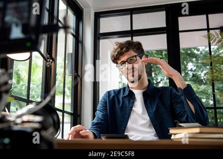 Young Caucasian man instructor recording video clip with carmera at home to share online in social media Stock Photo