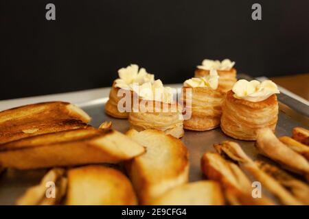 Baskets of puff pastry with butter and pate. Baking on a tray, black background. Stock Photo