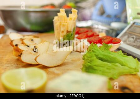 Cheese, fruit pear lemon salad on a wooden board. Bruschetta with tomatoes. Stock Photo