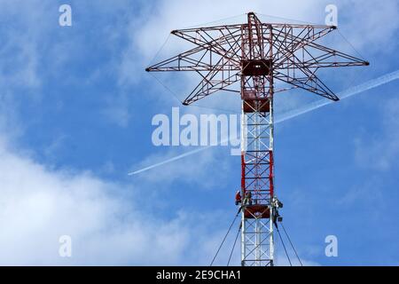 The workers are working high above on an old transmission tower. Stock Photo