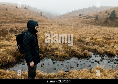 Young man exploring nature on a wet winter morning in the mountains Stock Photo