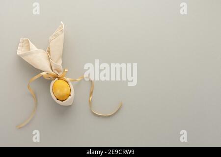 Abstract easter bunny from napkin and golden painted egg on gray background, easter festive concept Stock Photo