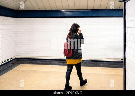 Stock photo of unrecognized woman talking on the phone while walking in metro station. Stock Photo