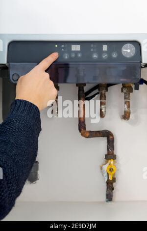 Woman hand switching on the heating boiler at home Stock Photo