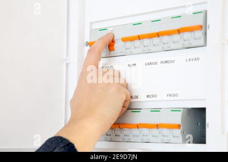 Woman hand switching off the fuse box at home. Words in spanish Stock Photo