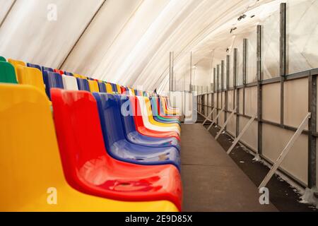 Multi-colored seats. Indoor ice rink. Sports stadium, stands for fans. Stock Photo