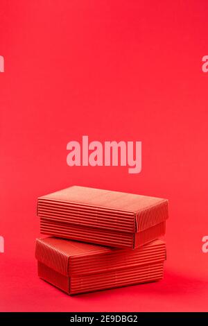 Monochromatic photo of two red closed corrugated cardboard boxes on red background. Valentine's Day gift packaging concept Stock Photo