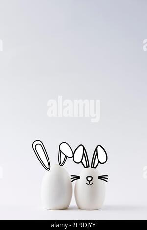 Close-up of some white eggs on white background with bunny ears. Easter bunny concept with bunny ears Stock Photo