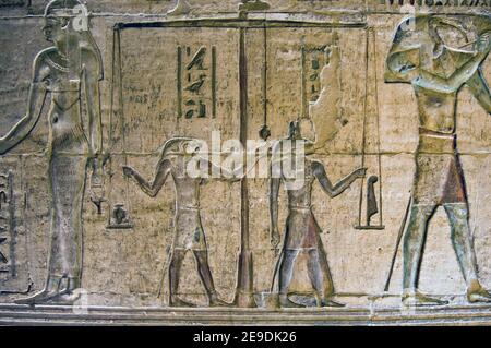 Ancient Egyptian bas relief carving showing the gods Horus and Anubis weighing a man's heart against a feather. Wall of the Temple of Deir el Medina a Stock Photo