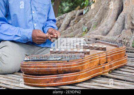 Close-up of a Cambodian musician playing a traditional khim musical instrument. A hammered dulcimer, or zither, style of instrument it has brass strin Stock Photo