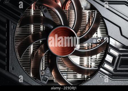 New shiny black GPU cooler with red center, close-up photo. This fan is mounted on a video card to cool the GPU and surrounding components Stock Photo