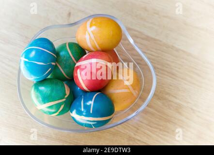 Pile of colorful painted homemade easter eggs with modern pattern in glass bowl on wooden table. Easter decoration, easter background. Stock Photo