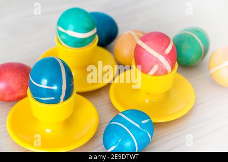 Colorful painted homemade easter eggs with modern pattern on yellow coasters on wooden table. Easter decoration, easter background. Stock Photo